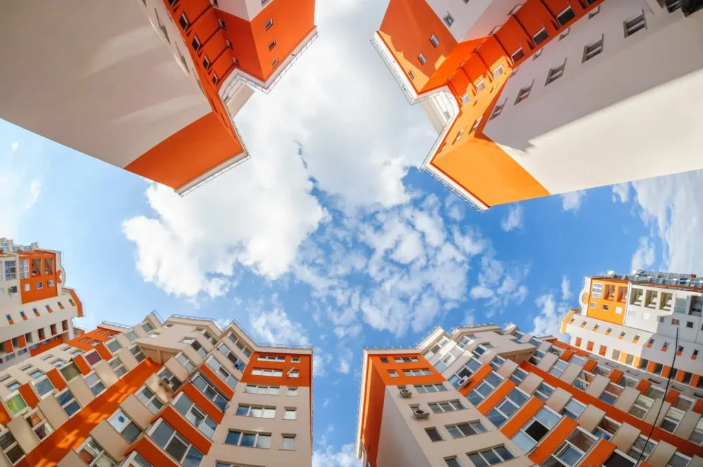 Looking up at four tall orange and white apartment buildings against a blue sky with white clouds used for Marketing for Accountants.